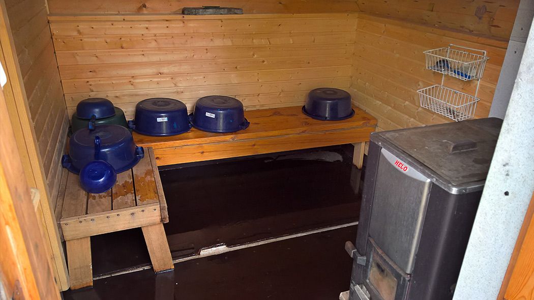 Saunan pesutuvassa on vesipata ja pitkät puupenkit joiden päällä on vateja.