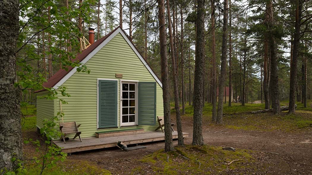Pieni lautarakenteinen tupa mäntymetsässä.