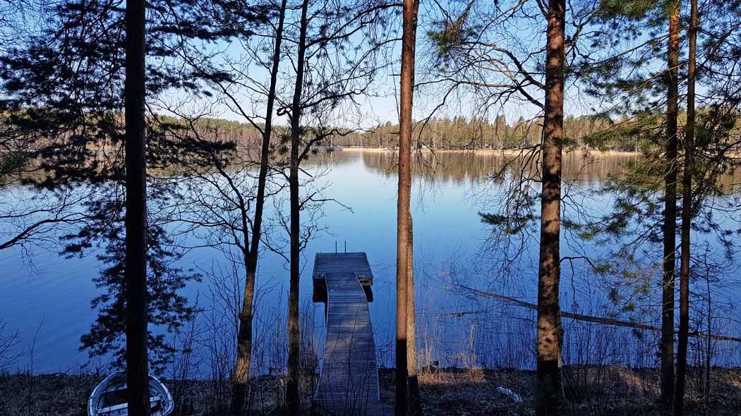 Järvimaisemaa ja laituri saunalta nähtynä. Rannassa on soutuvene.