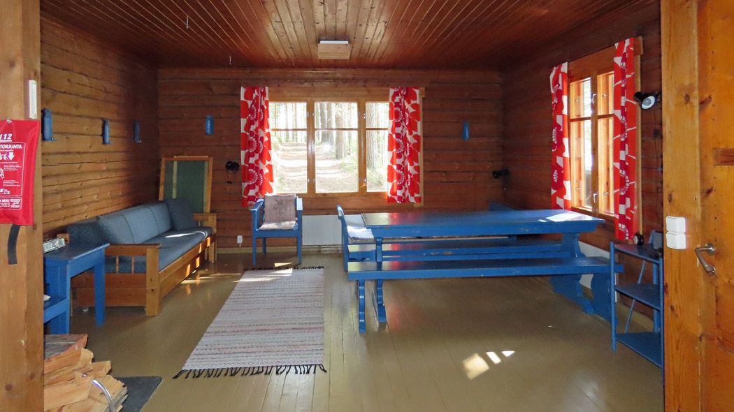 Sinisiä puukalusteita ja sohva tuvassa.