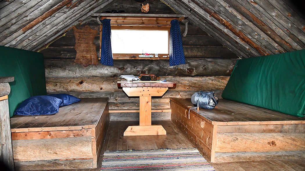 Inside the cabin there are two sleeping places with a table between them. A small window has curtains.