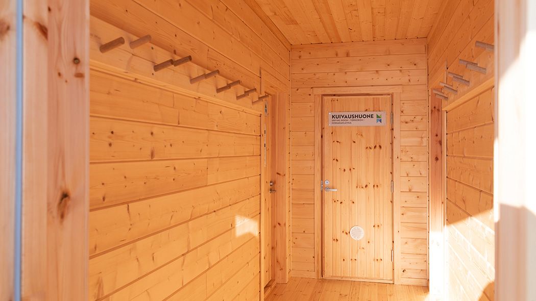 The hallway of the hut. The hallway has a coat rack and a door.
