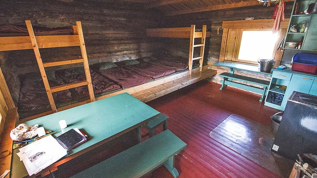 Kaksikerroksinen makuulaveri ja pöytiä tuvassa.
