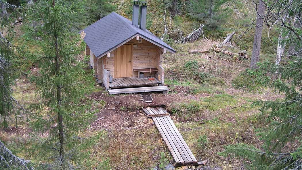 Liten bastubyggnad i skogen.