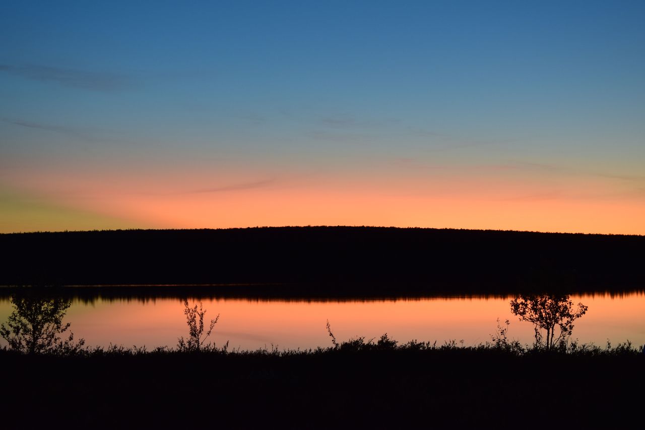 Peilityyni järvi ja auringon laskun värjäämä taivas.