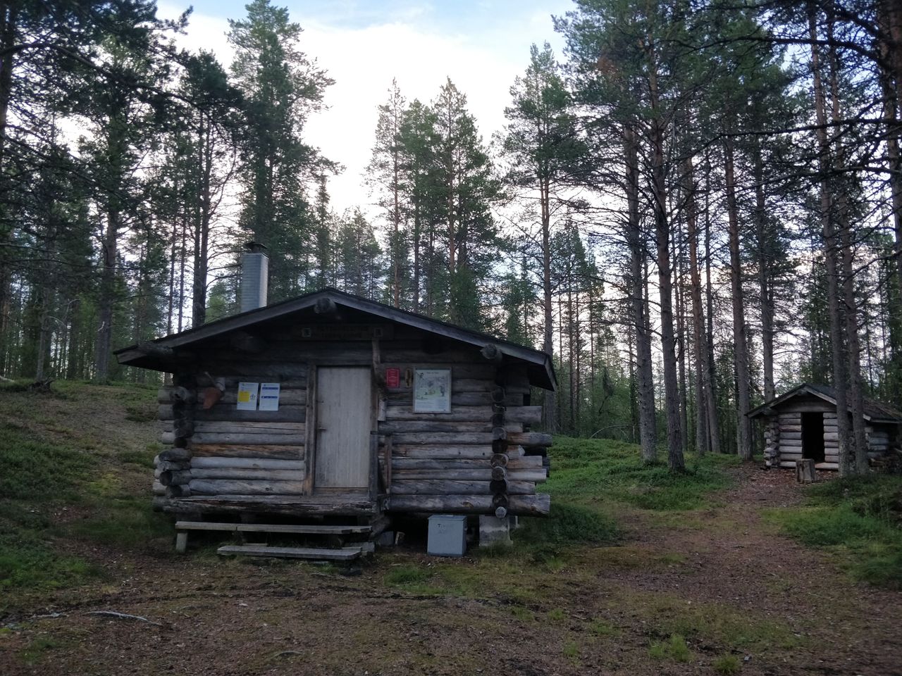En rundtimrad ödestuga mitt i skogen.