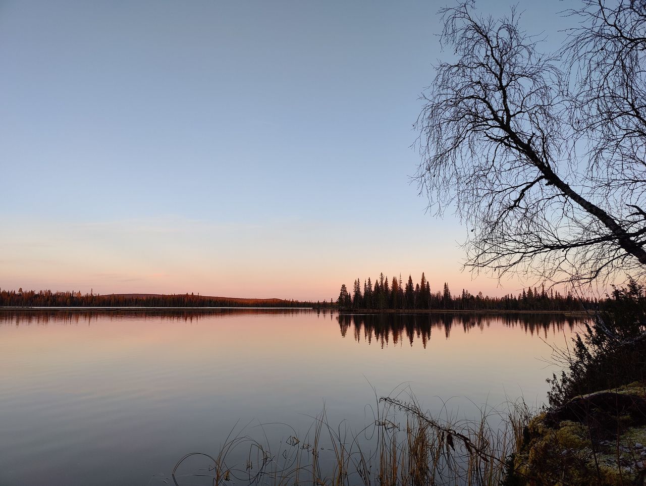 Rauhallinen ja tyyni järvimaisema auringolaskun aikaan. 