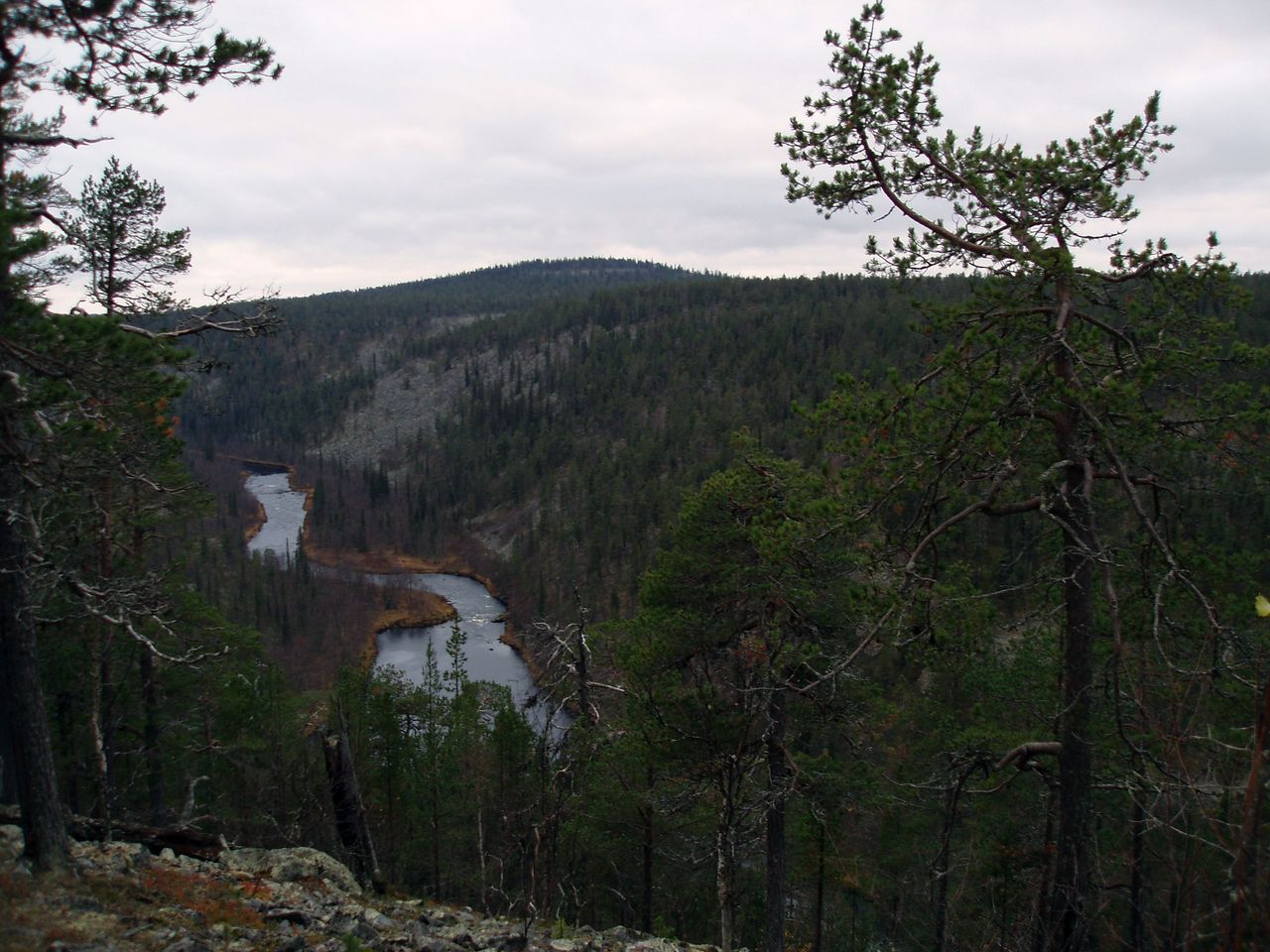Tunturimaisema pilvisellä säällä. Mutkainen joki kiemurtelee tunturin juurella.