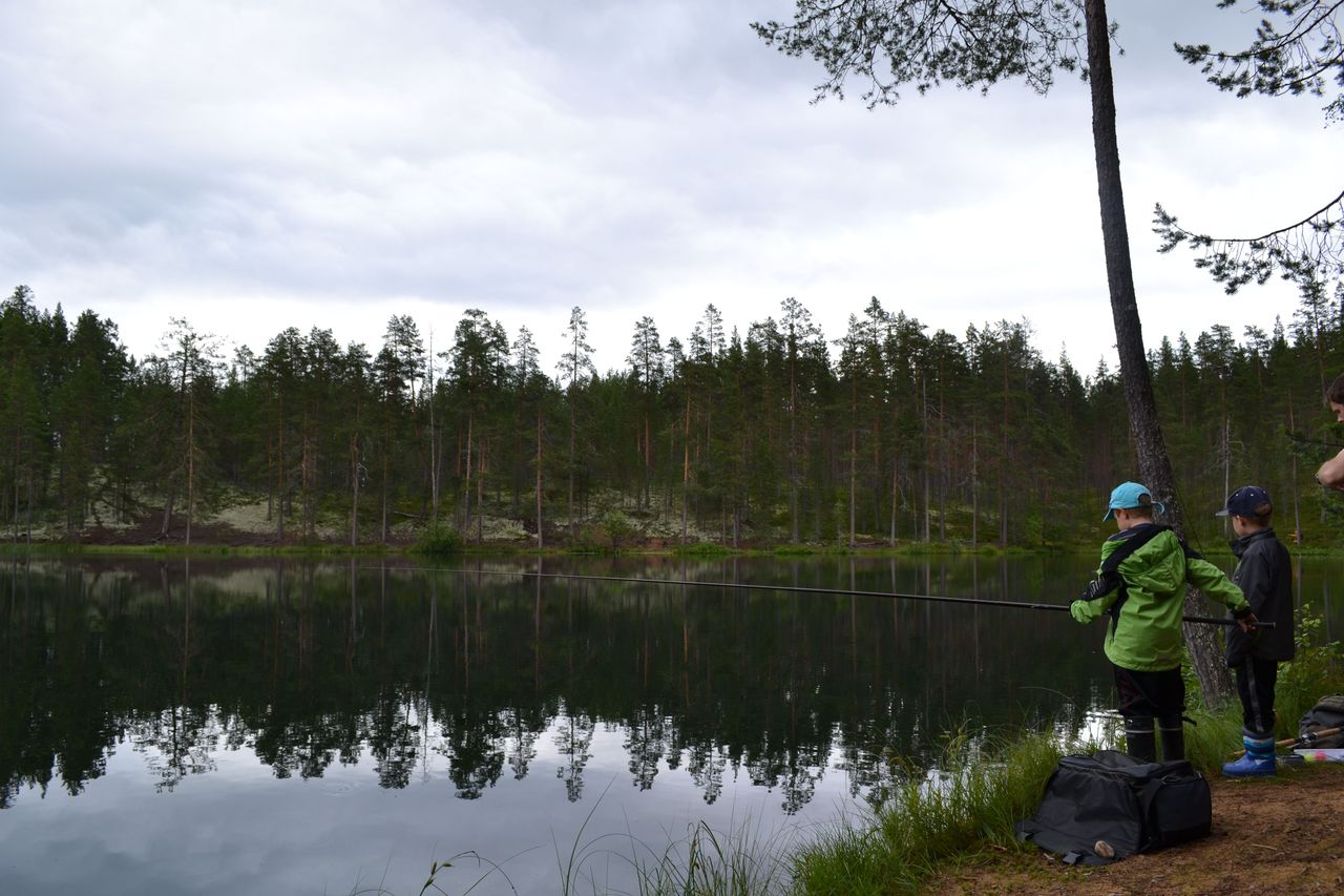 Kaksi nuorta kalastajaa järven rannalla.