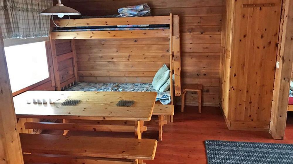 Tuvan perällä kerrossänky ja vaatekomero. Etualalla on pöytä.